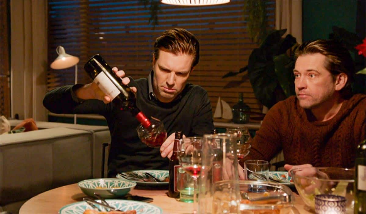 Scène uit Goede Tijden, Slechte Tijden waarin Stefano tijdens een etentje met Rik wijn inschenkt.