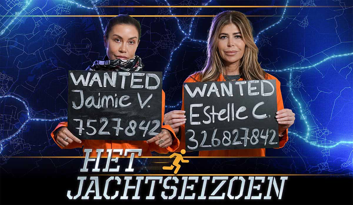 Het Jachtseizoen deelnemers Jaimie Vaes en Estelle Cruijff poseren in oranje pakken met een ‘wanted bord’ voor zich. Credits: (c) Talpa TV