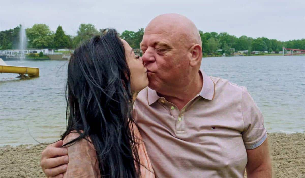 Peter Gillis kust zijn nieuwe vriendin Wendy van Hout terwijl hij voor een meer van het Oostappen vakantiepark staat tijdens de opnames van realityserie Massa is Kassa.