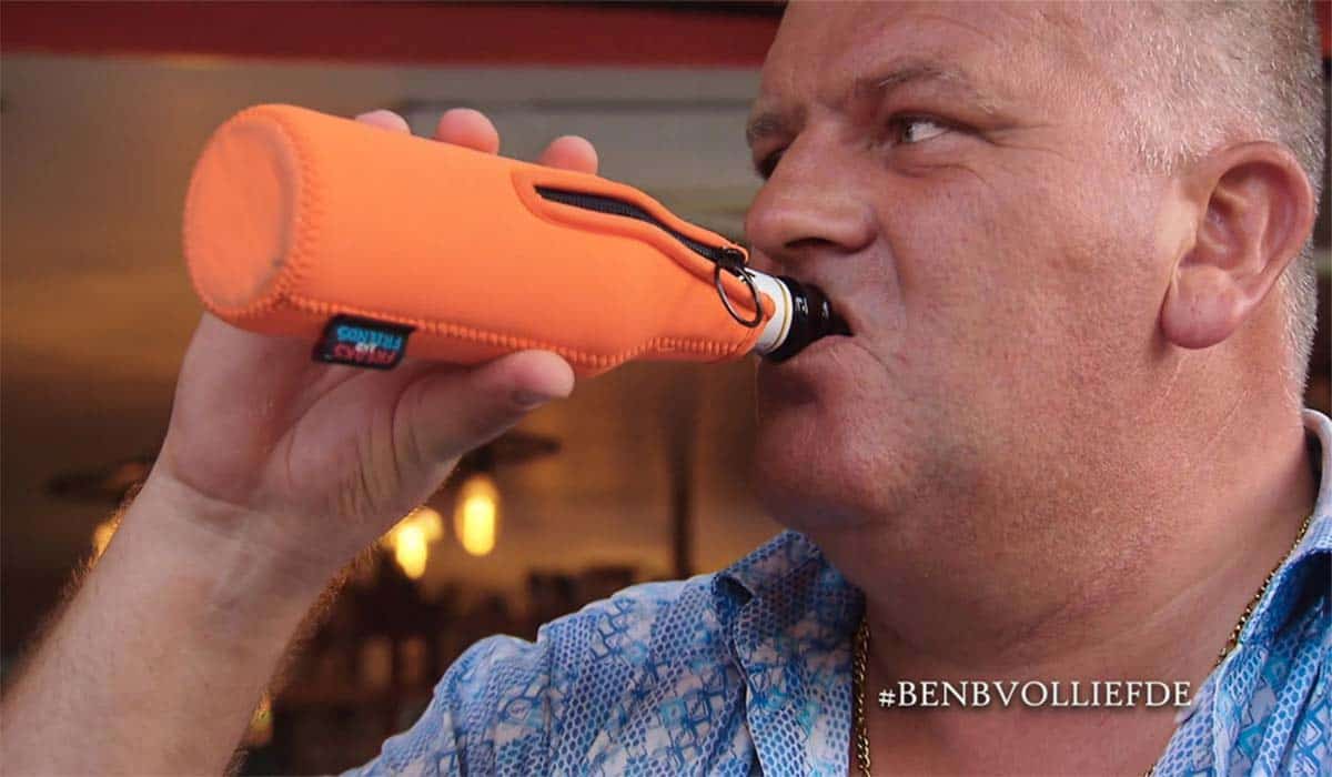 B&B Vol Liefde 2023 deelnemer Martijn Bolhoeve neemt een slok uit een fles met een oranje hoes eromheen.