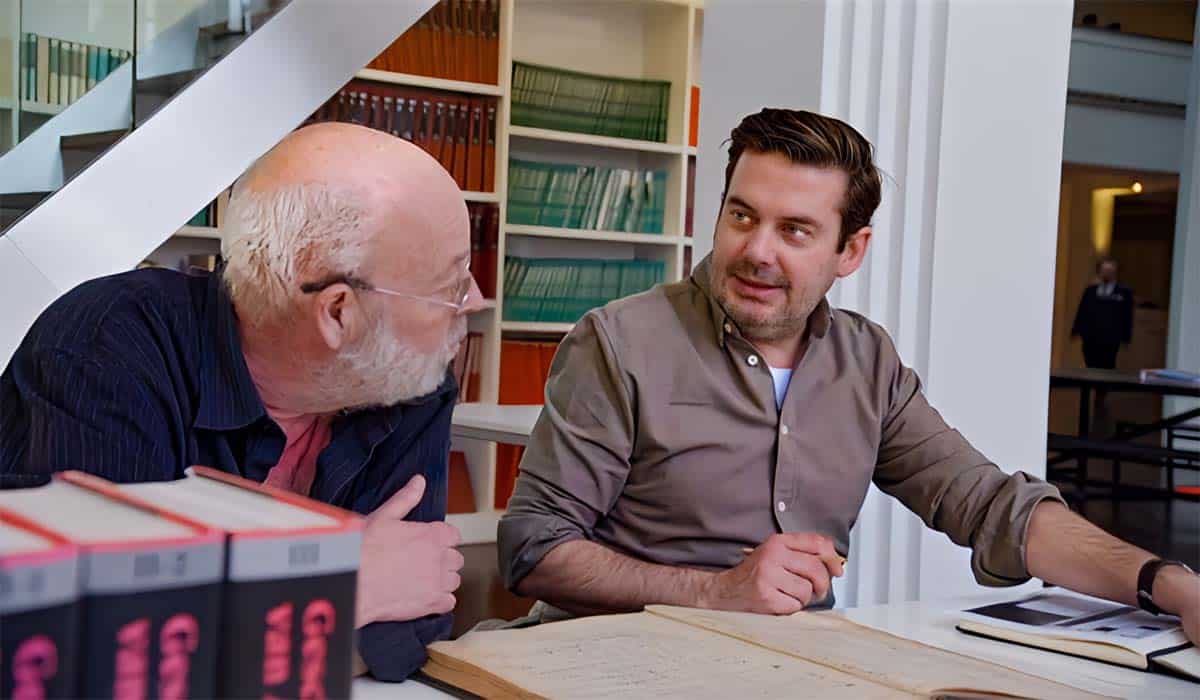 Ruben Nicolai zit aan tafel in het archief en praat met oudere man in De Erfgenaam 2023.