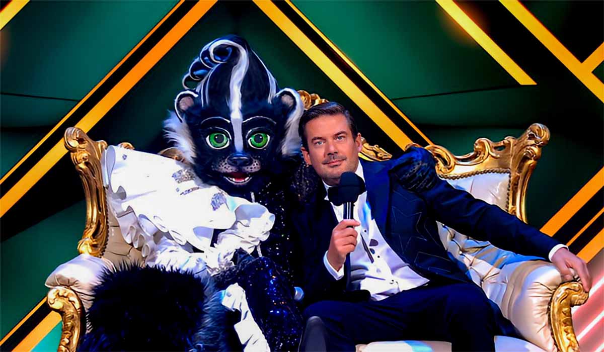 Het stinkdier en presentator Ruben Nicolai zitten gearmd op een barok bank in het RTL4 programma The Masked Singer 2023.